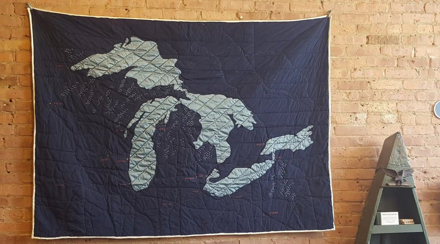 Quilted wall hanging depicting the Great Lakes in navy blue and light blue fabric.