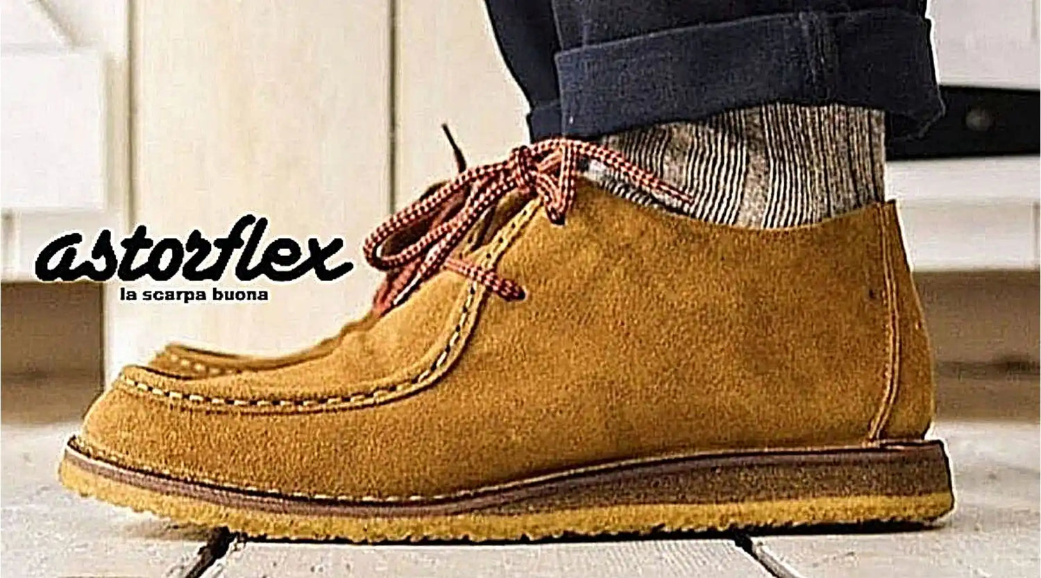 Tan suede moccasin-style boot with striped sock visible above the ankle.